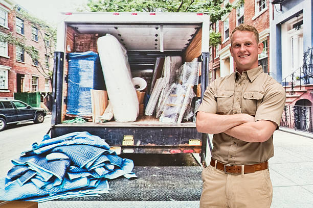 Déménageur professionnel qui se tient devant son camion rempli de cartons avant un déménagement