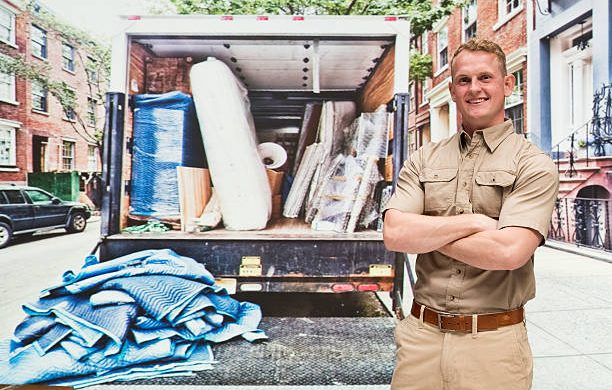 Déménageur professionnel qui se tient devant son camion rempli de cartons avant un déménagement