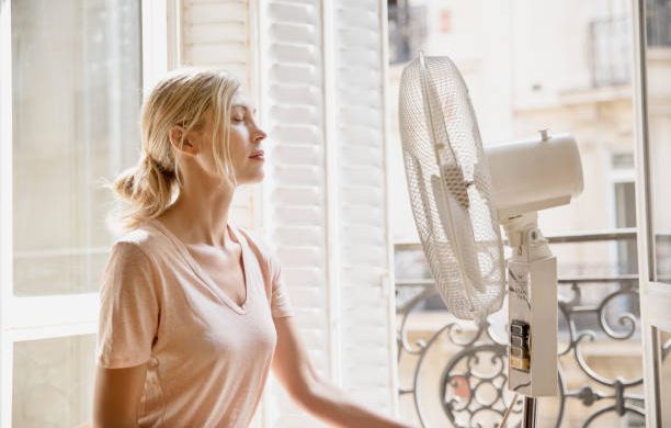 Jeune femme qui utilise un ventilateur pour se rafraîchir pendant la canicule