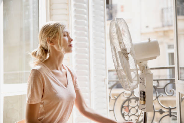 Jeune femme qui utilise un ventilateur pour se rafraîchir pendant la canicule